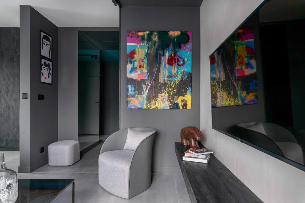 弗罗茨瓦夫Niegaleria Apartament的客厅配有椅子和墙上的绘画作品