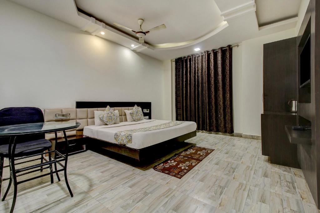 博帕尔FabHotel CSFC Near Bhopal Railway Station的酒店客房配有床、桌子和桌子。