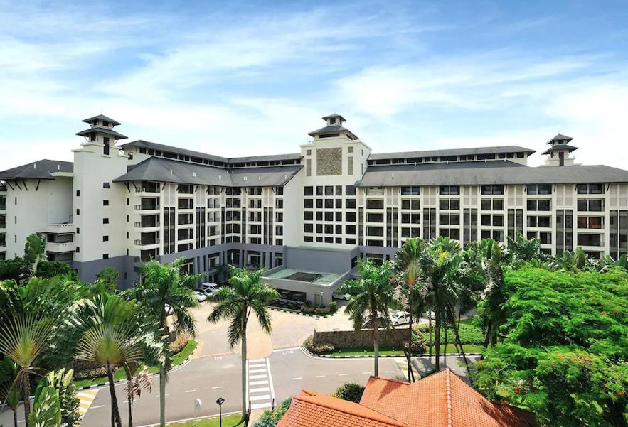 士姑来Garden View Pulai Springs Resort的一座白色的大建筑,前面有棕榈树