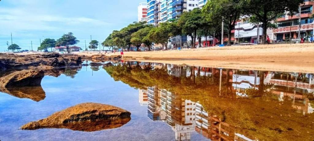 瓜拉派瑞Vem pra cá! Localização Privilegiada!的水面上海滩和建筑物的反射