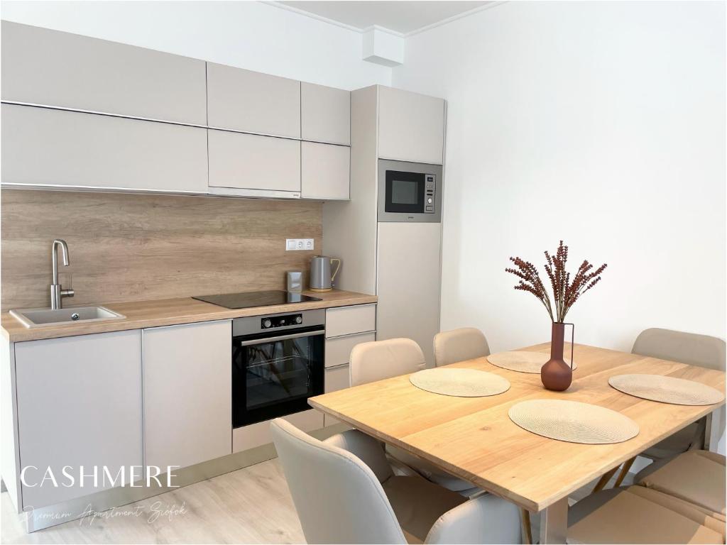 希欧福克CASHMERE Premium Apartment的厨房配有木桌和白色橱柜。