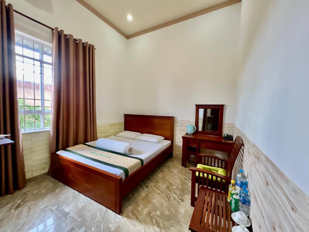 朔庄XUÂN HUỲNH 3 Hotel的一间卧室配有一张床、一张桌子和一个窗户。