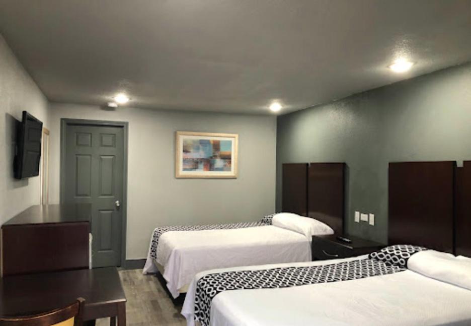 尼斯维尔Budget Inn Valparaiso/Niceville @ Eglin AFB & Destin-FWB Airport的酒店客房带两张床和一张桌子,还有一间房间