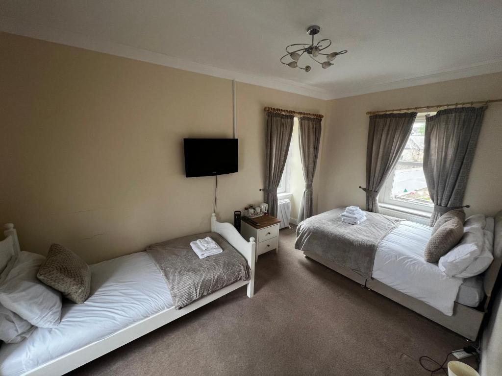 CarstairsThe Village Inn的一间卧室设有两张床,墙上配有电视。