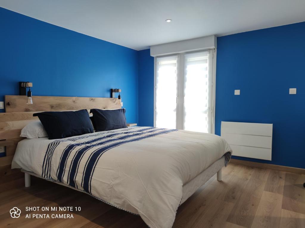 贝尔热拉克Appartement de charme en plein coeur de Bergerac的一间拥有蓝色墙壁和一张大床的卧室