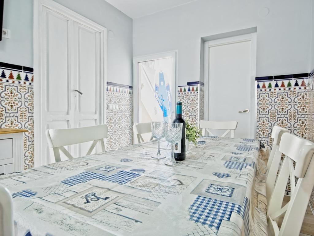 Mareny BarraquetasCASA EN LA PLAYA VALENCIA EL PERELLO的一间白色的用餐室,配有一张桌子和一瓶葡萄酒