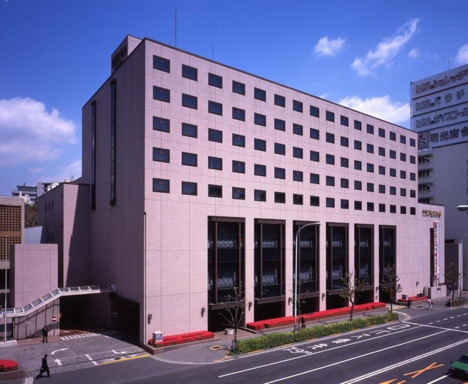东京Hotel Grand Hill Ichigaya的街道上有许多窗户的大型白色建筑