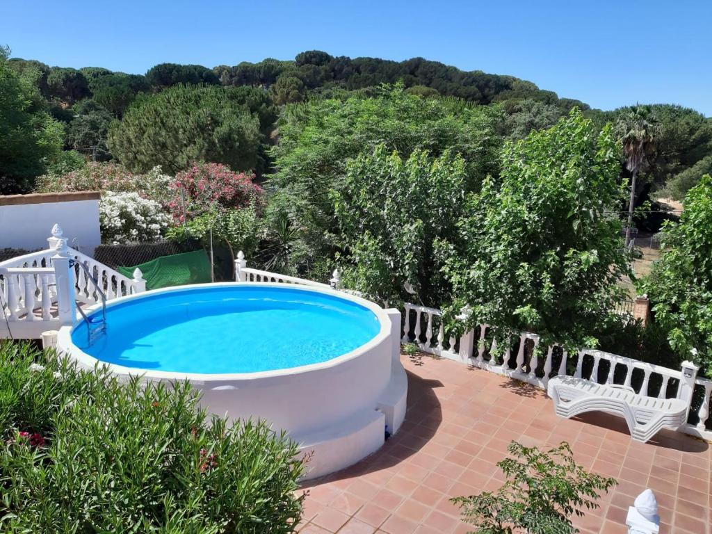 科尔多瓦Chalet rural La Solana, a 12 Kilómetros de Córdoba en plena sierra, con piscina的后院的游泳池,设有白色的围栏和白色的长凳