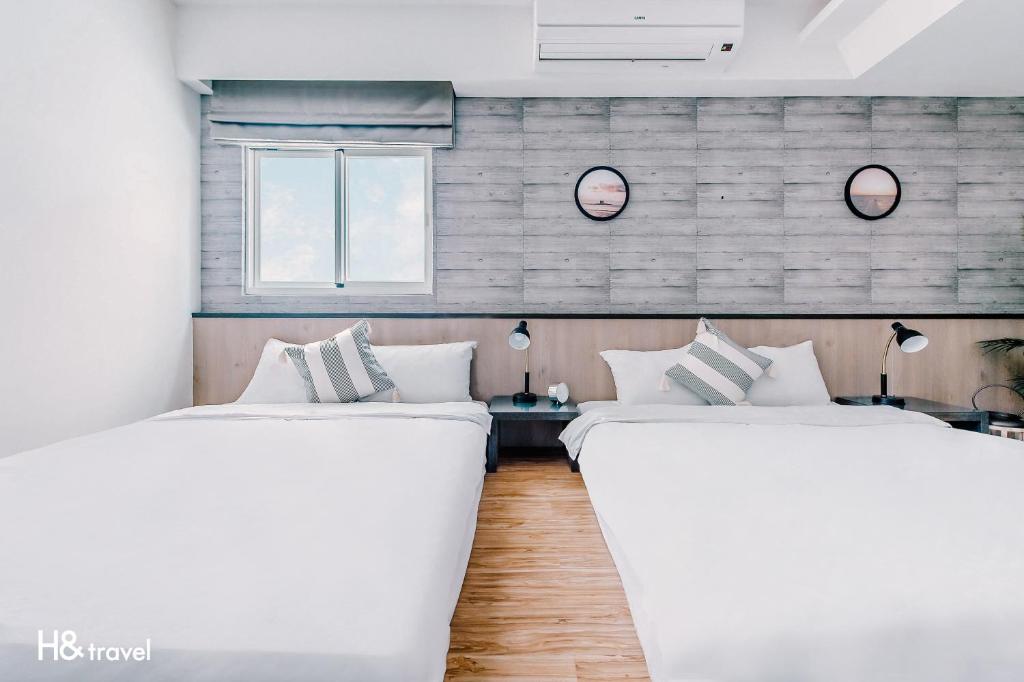 马公澎湖臨海居會館 l 電梯的带2扇窗户的客房内的2张白色床