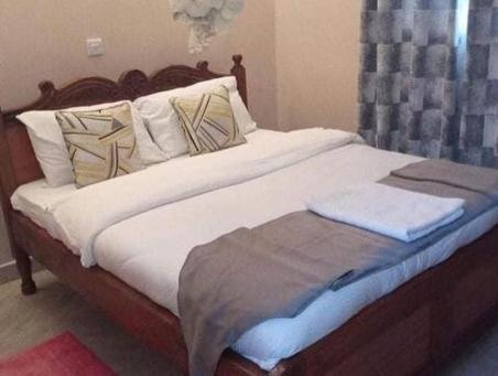 基塔莱Stay.Plus Villa Serene Kitale的卧室内的一张带白色床单和枕头的床
