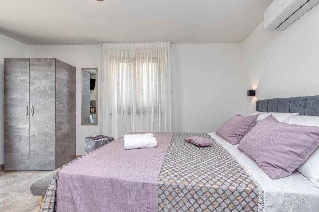 波雷奇Rooms Nilda的白色卧室配有一张带紫色枕头的大床