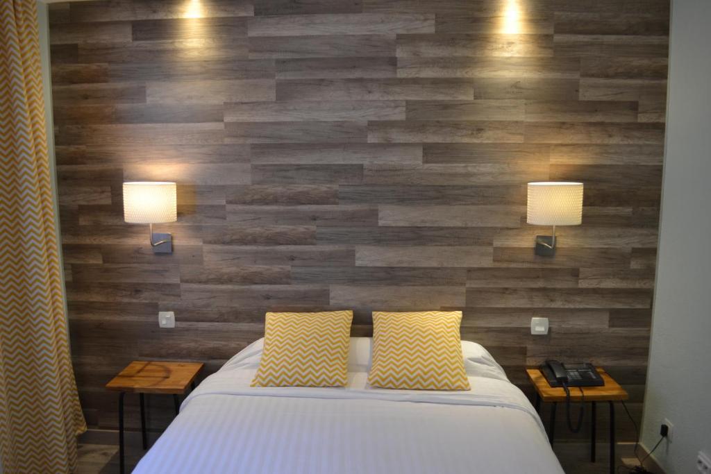 艾克斯莱班喙末酒店的一间卧室设有木墙、一张床和两盏灯。