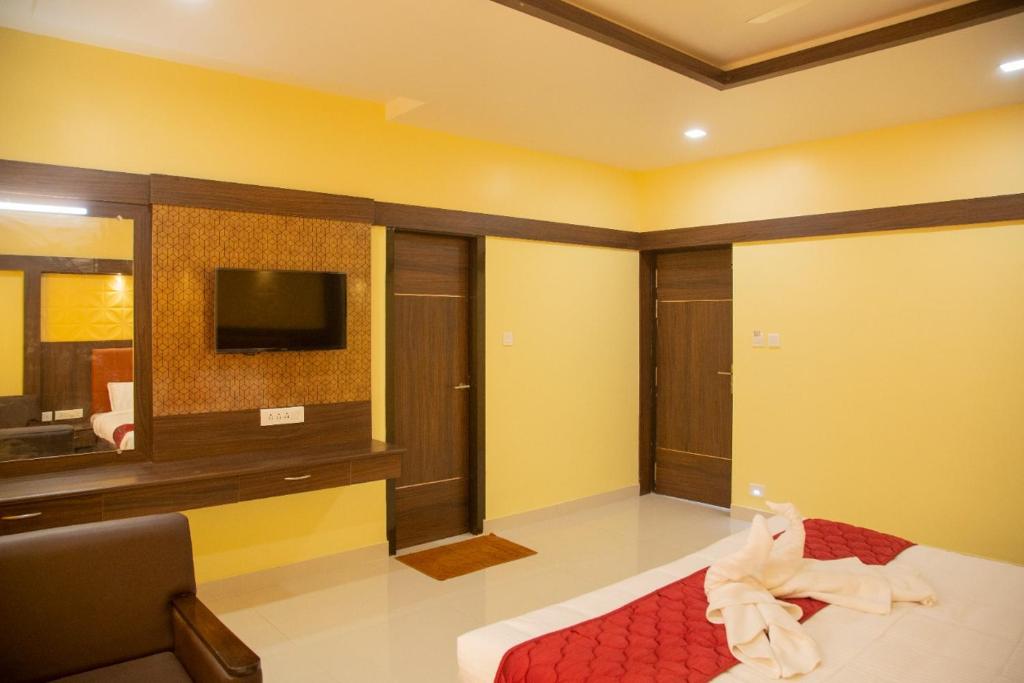 库姆巴科纳姆sri balaji grand hotel的客房设有床、电视和沙发。