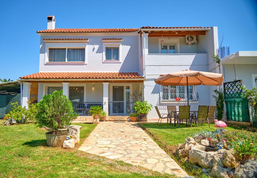 罗达Noufris House Roda Corfu的一座带遮阳伞和庭院的房子