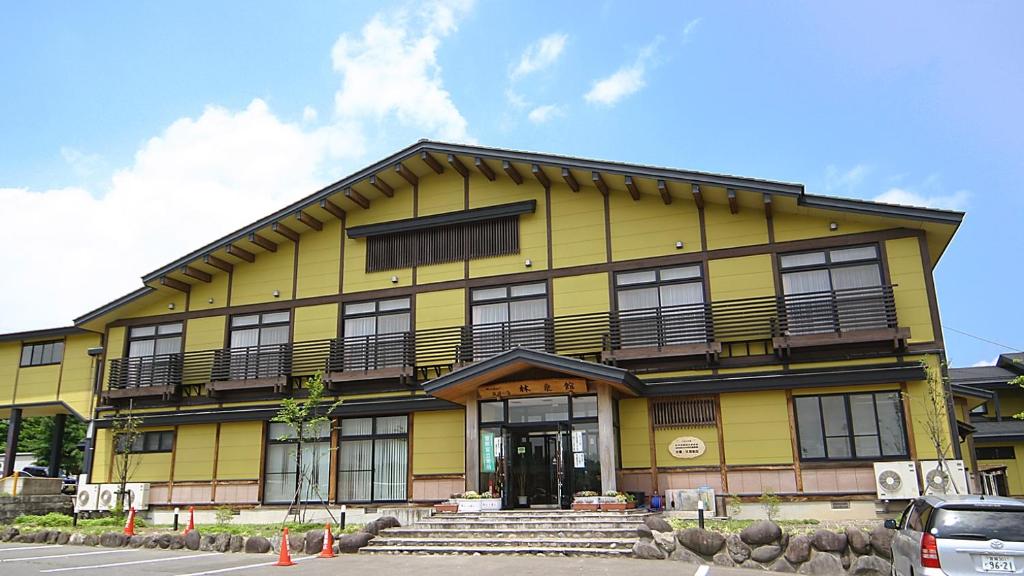 大崎市Tabinoyado Yakurai Rinsenkan的前面设有门廊和楼梯的黄色建筑