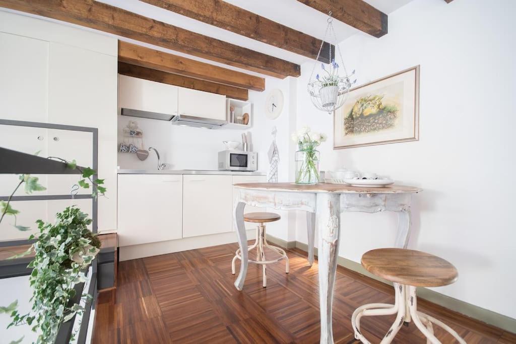 米兰Romantic loft Porta Venezia MILAN的厨房配有一张桌子和两张凳子