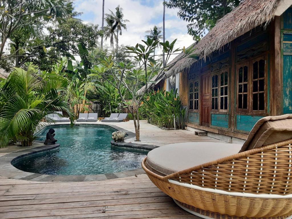 吉利阿尔Musa Bintang Villas and Bungalows Gili Air的房屋旁的游泳池,带藤椅
