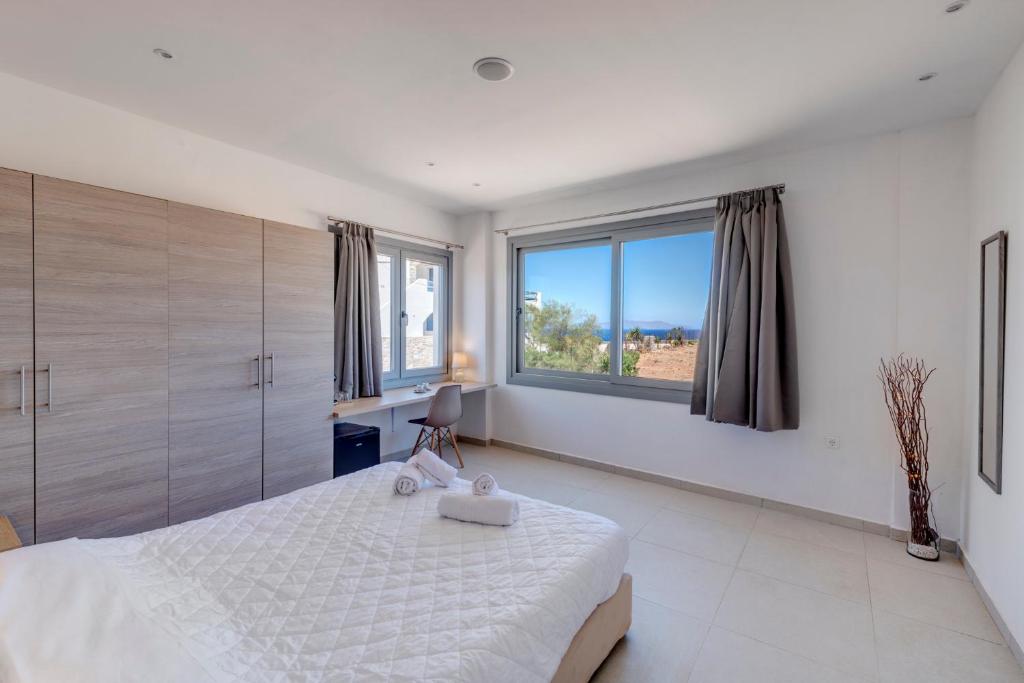 阿诺锡罗斯Chrysonisos Suites with Sunset & Seaviews near Kini的白色卧室设有大床和大窗户