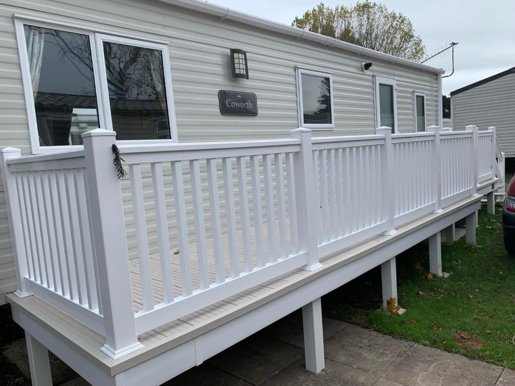 Lytchett MinsterNew 2 bed holiday home with decking in Rockley Park Dorset near the sea的一个小房子上白色的乙烯基栅栏