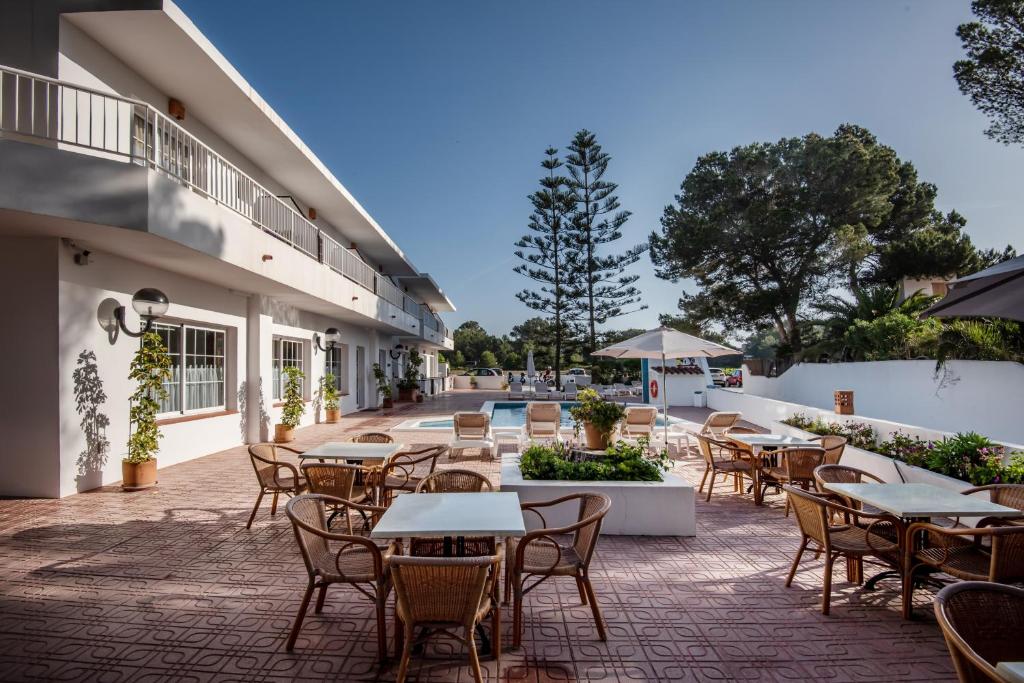 米乔尔海滩Hostal Es Pi - Emar Hotels的一个带桌椅的户外庭院和一个游泳池
