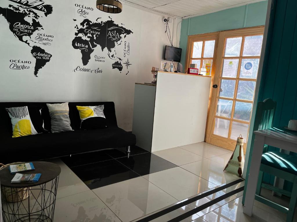 拉塞雷纳Hostal Avenue的客厅配有黑色沙发和墙上的世界地图