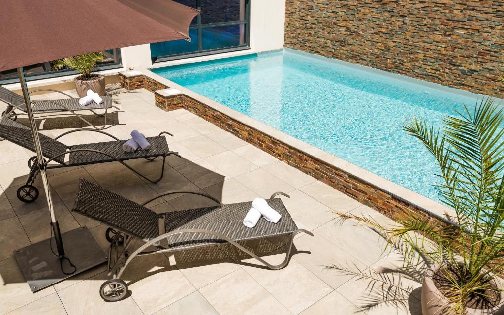 比亚里茨尤金妮娅露台拉格朗日假日酒店****的一个带两把椅子和遮阳伞的游泳池