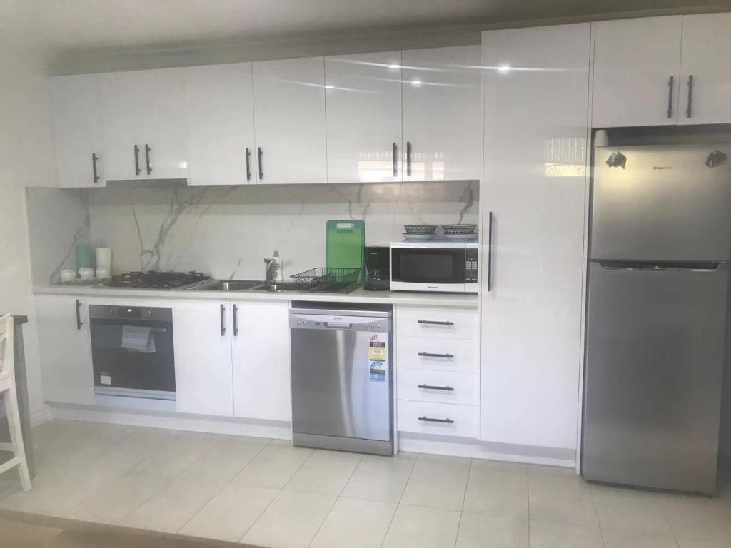 奥克利Oakleigh Private unit的厨房配有白色橱柜和不锈钢用具