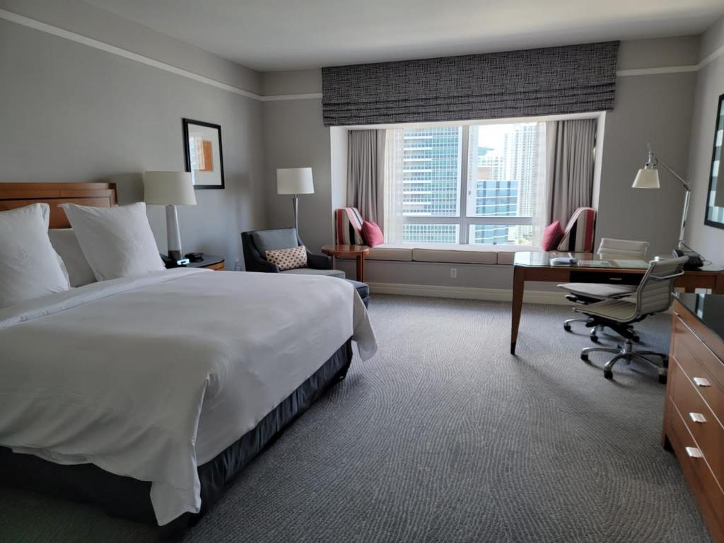 迈阿密Four Seasons Suite的配有一张床、一张书桌和一扇窗户的酒店客房