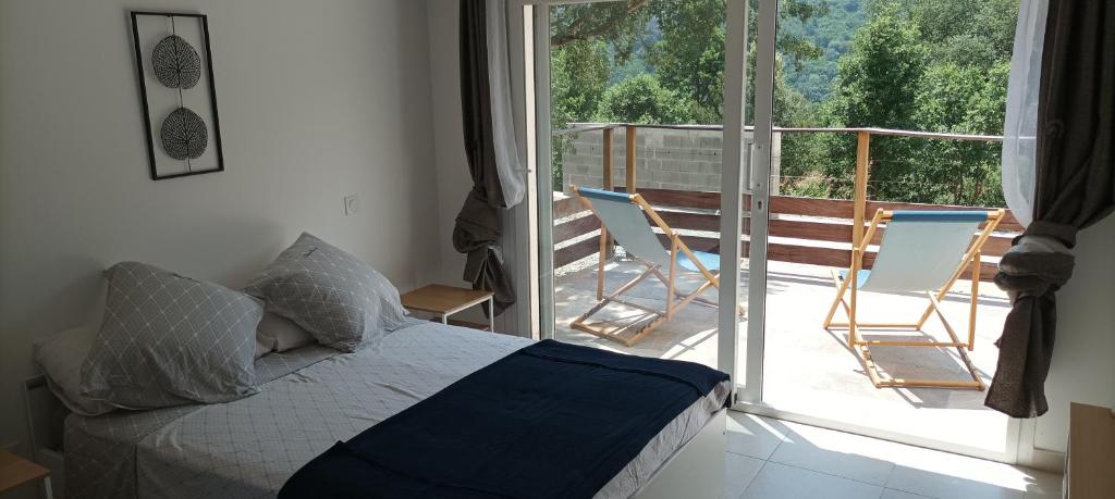 BigornoMaison 38m2 15min de Corte 30min de Bastia的一间卧室配有一张床,阳台配有椅子