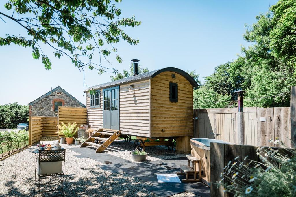 朗塞斯顿Boutique Cornish Shepherd's Hut with Hot Tub的一个带栅栏的院子内的小木屋