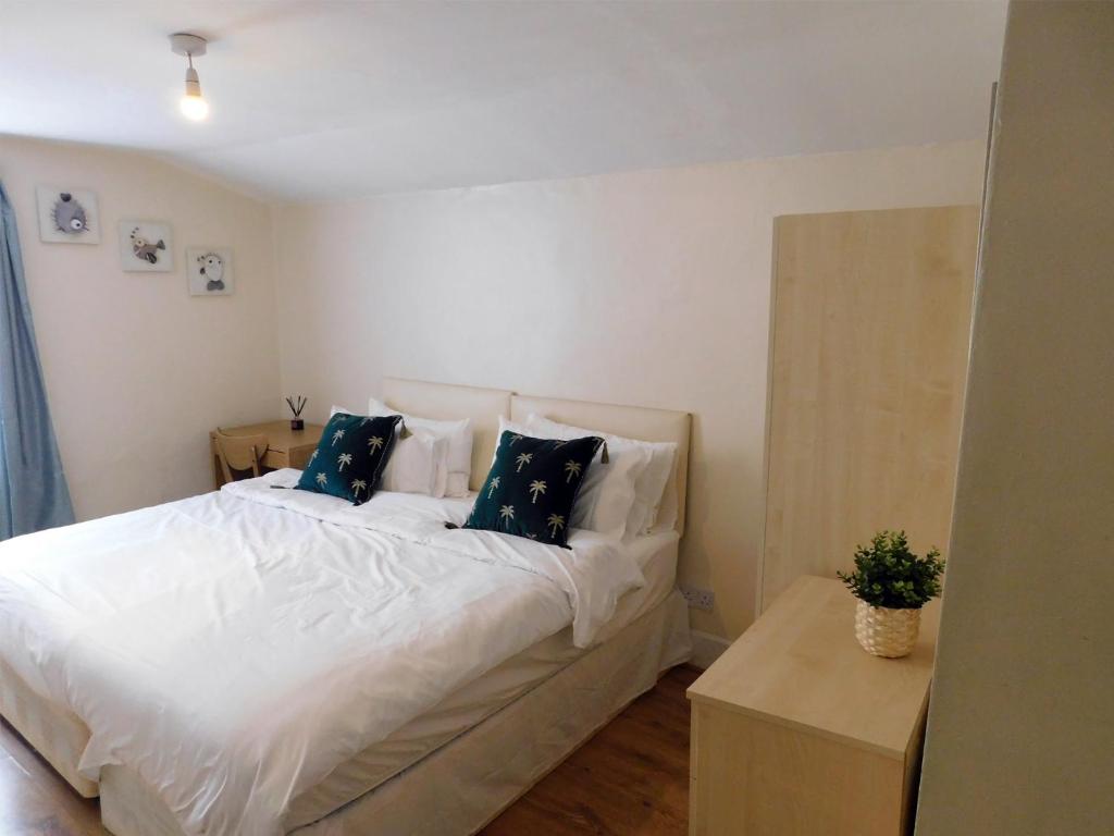 伦敦Entire 4 bedroom Terrace house in London的卧室配有带蓝色枕头的大型白色床