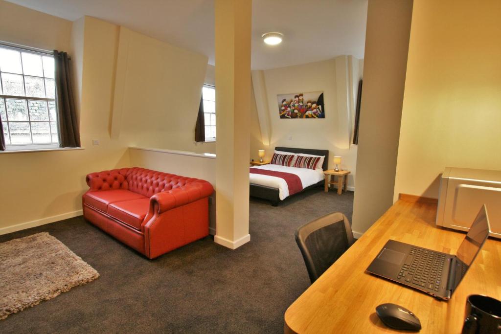 格洛斯特格洛斯特中央酒店的带沙发、床和书桌的客房