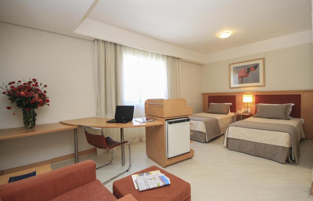 圣保罗比那尔套房酒店的酒店客房设有两张床和一张带笔记本电脑的桌子。