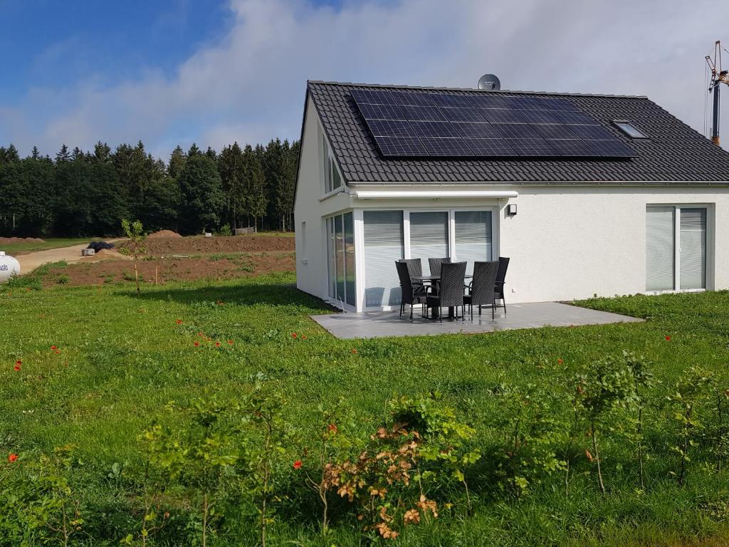 普吕姆Ferienhäuser Prüm的房屋设有一组椅子和太阳能屋顶