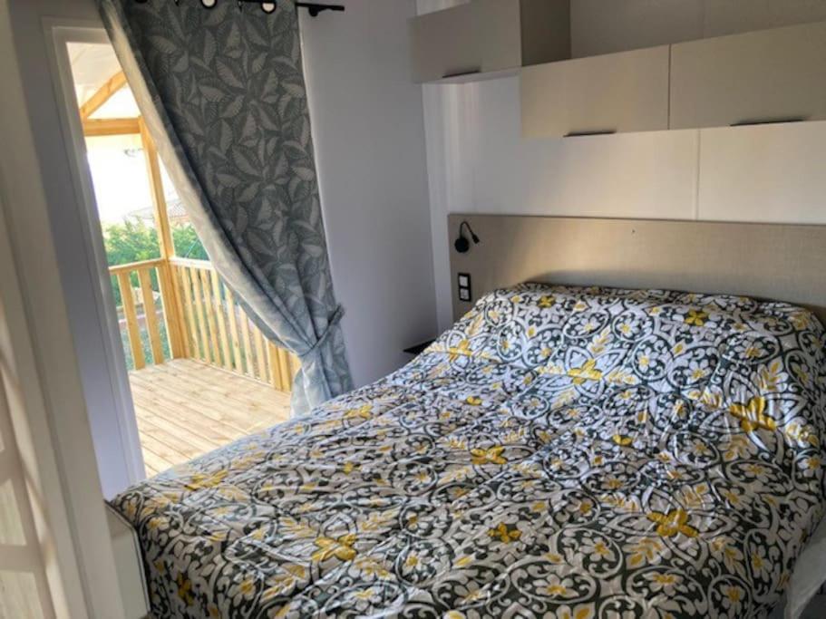圣拉斐尔Camping L'ILE D'OR的一间卧室配有一张带鲜花棉被的床和窗户。