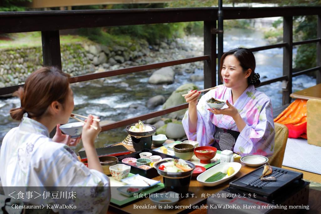 伊豆龙田日式旅馆的坐在餐桌旁吃食物的几个人