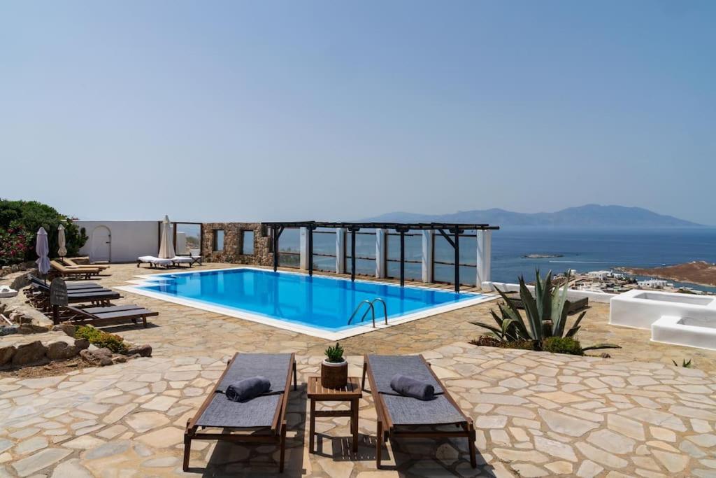 圣爱奥尼斯米科诺斯Nefes Residence 2 bedroom villa的一个带两把椅子的游泳池,背景是大海