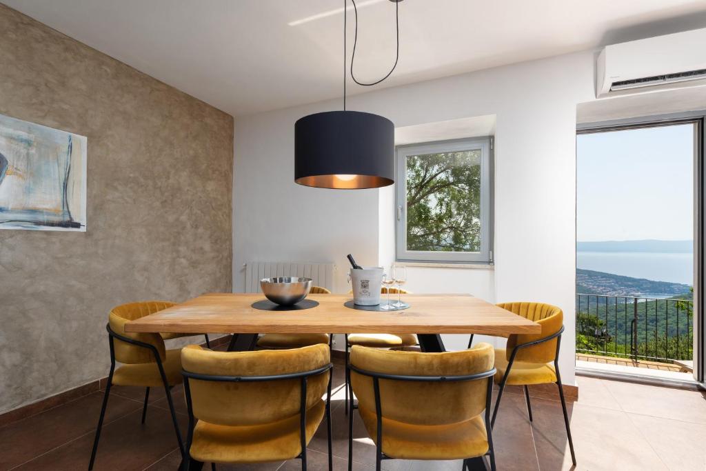 拉宾CASA GIUSEPPE Luxury house with an amazing view的一间带木桌和黄色椅子的用餐室