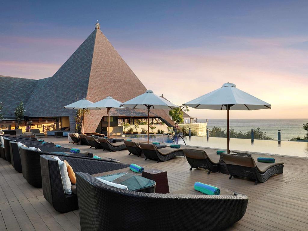 库塔库塔海滩遗产酒店 - 由雅高酒店集团管理的一间带桌椅和遮阳伞的餐厅