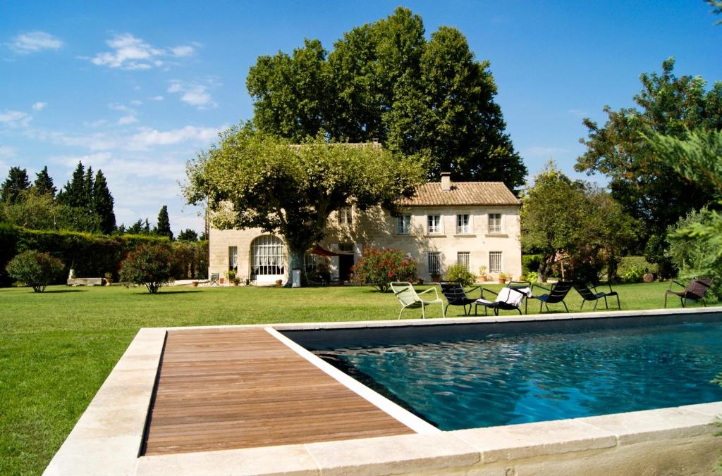 阿维尼翁La ferme de gigognan的一个带椅子的游泳池和一个背景房子