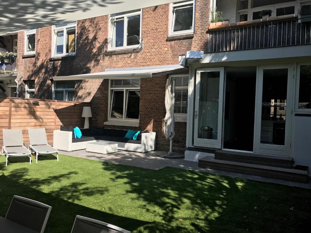 阿姆斯特丹Amsterdam, 120 sqm Design flat with garden, close to all!的一座建筑前的庭院,庭院内设有椅子和草坪