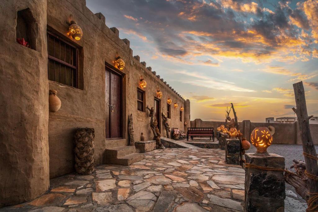 阿尔哈姆拉Canyon Rest House Jabal Shams的一座建筑,有石头人行道,背面有日落