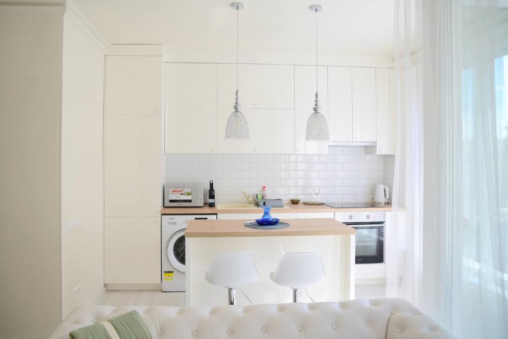 塞格德Cloé Apartman的白色的厨房配有桌子和两把椅子