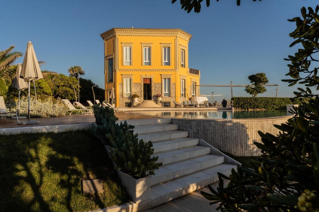 阿尔盖罗莫斯卡迷人之家别墅住宿加早餐旅馆的一座黄色房子,在游泳池前设有楼梯