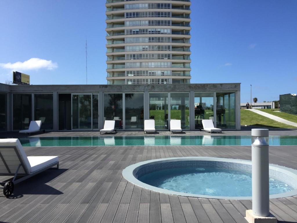 蒙得维的亚Faros de Carrasco Apartments的一座带椅子的游泳池以及一座建筑