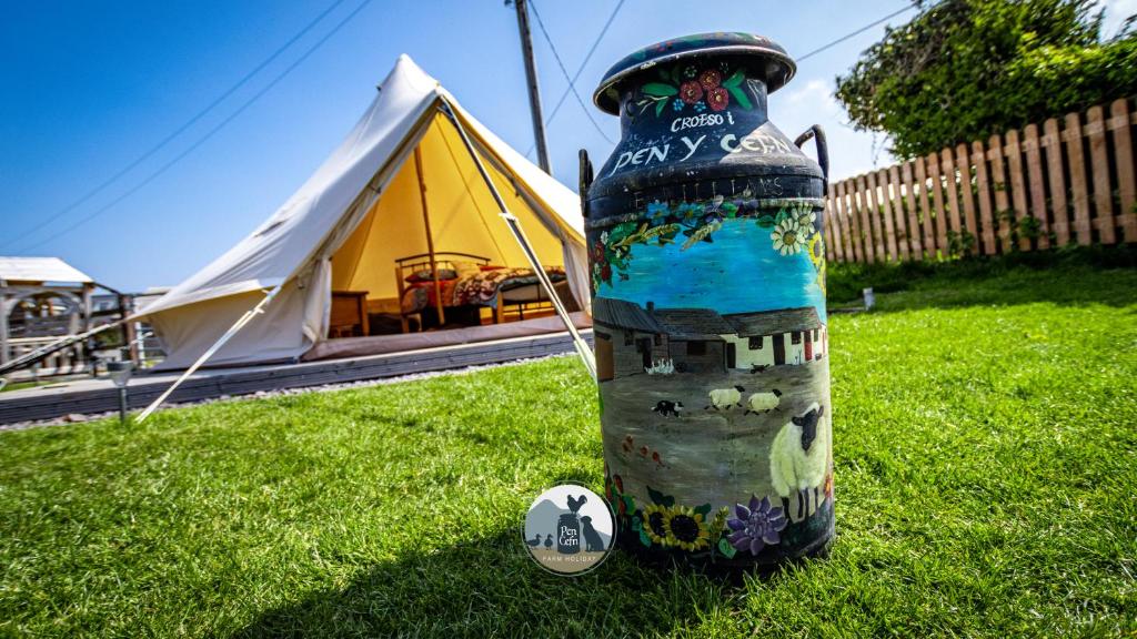 阿贝尔格莱Yr Wyddfa Bell Tent - Pen Cefn Farm, Abergele, Conwy的帐篷旁边的草丛里的一瓶