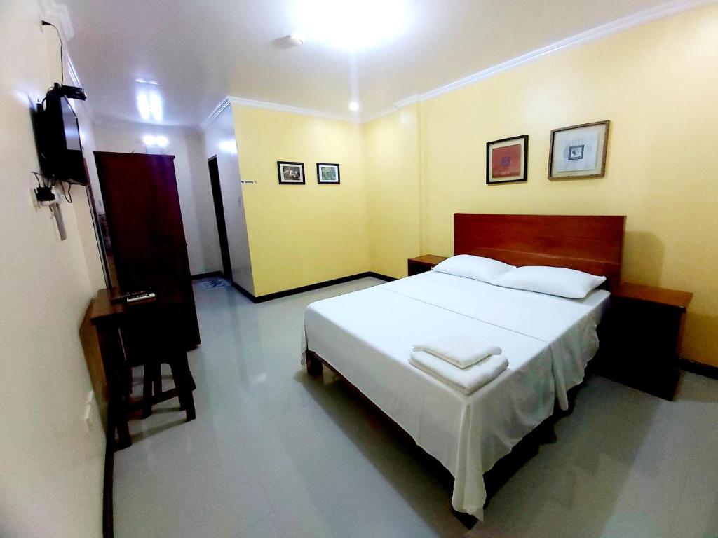 公主港Golden Pension House,Palawan的卧室配有一张白色大床和电视。