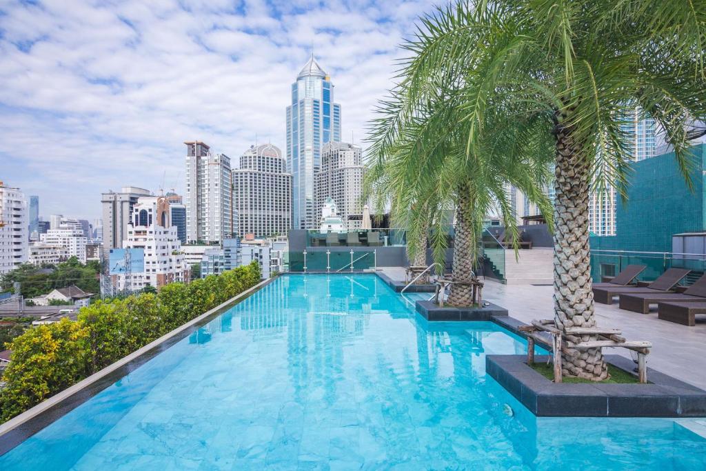 曼谷SureStay Plus by Best Western Sukhumvit 2的一座棕榈树游泳池,位于一座建筑的顶部