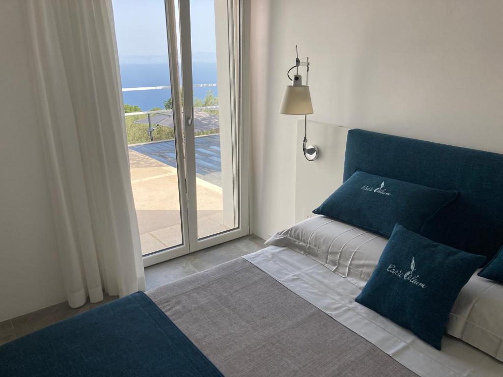 阿纳卡普里“CapriOleum” esclusive place的窗户间内的一张带蓝色枕头的床