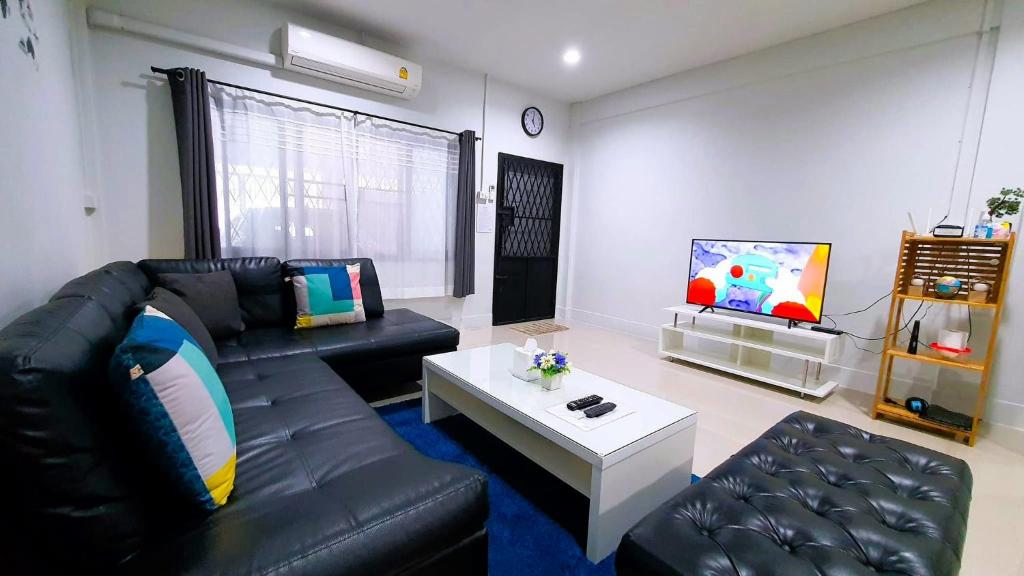合艾HDY 16 Home的客厅配有黑色真皮沙发和电视